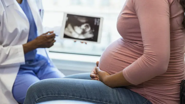 Gestante em consulta de pré-natal, com imagem de ultrassom ao fundo